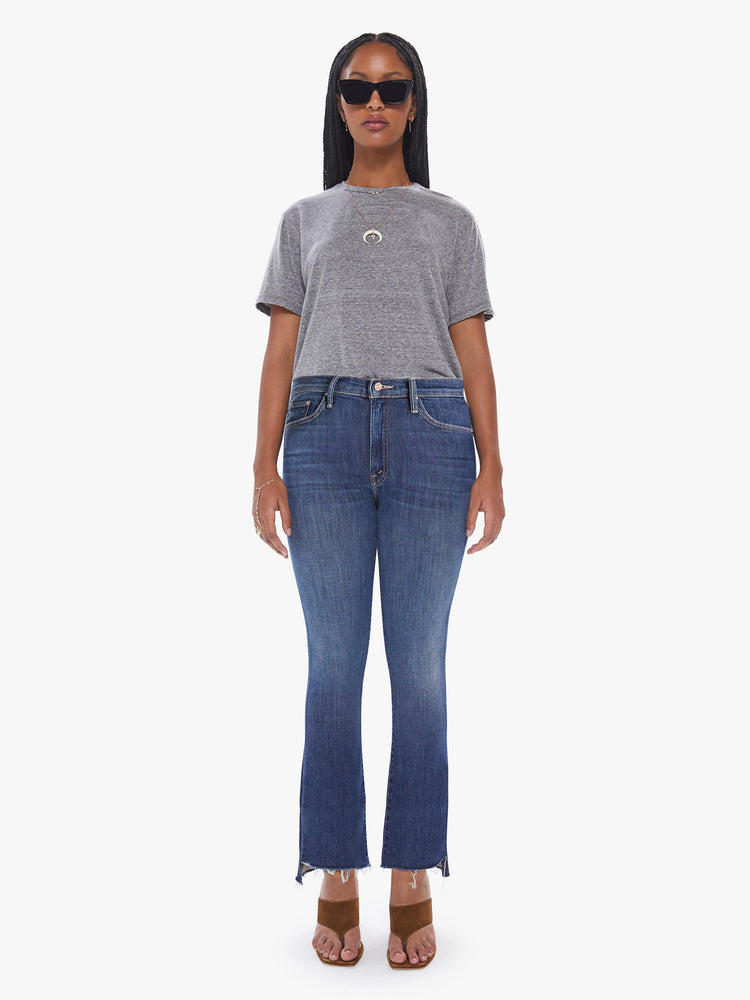 Front view of a womens high rise jean in a medium blue wash, featuring a raw crop step fray hem.