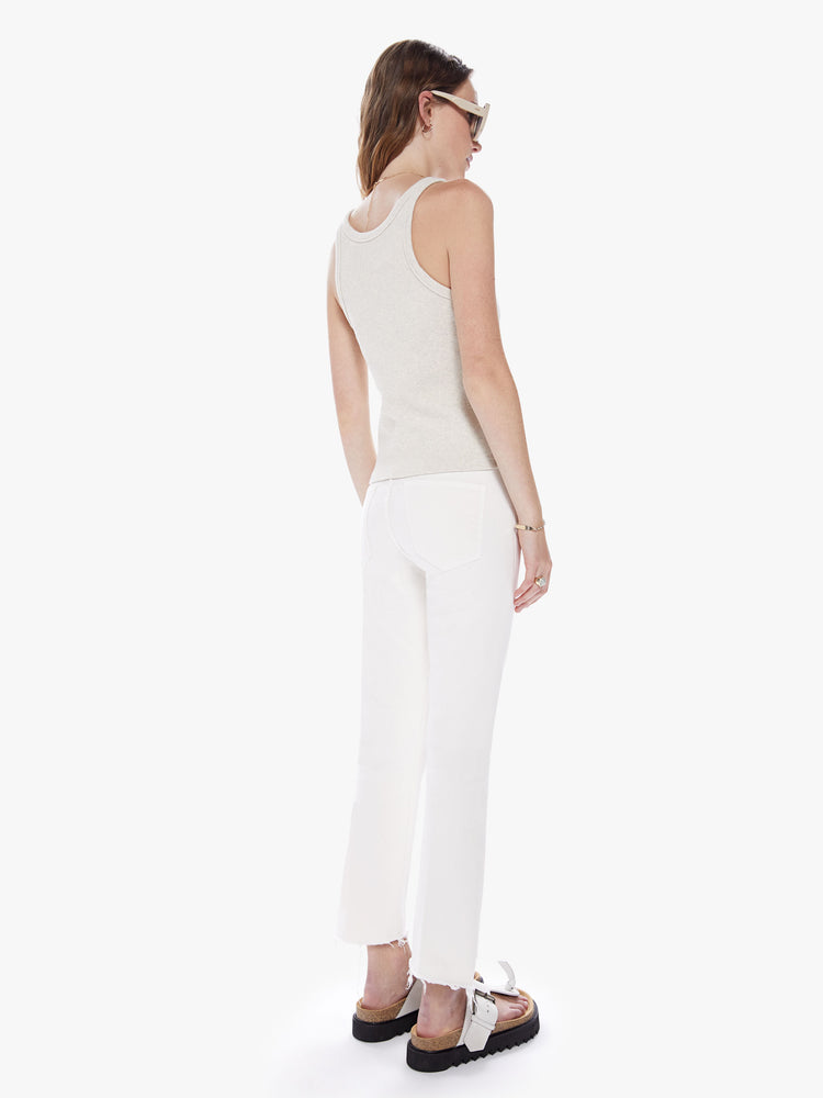 Back full body view of a woman in a high waisted bootcut hits at the ankle with a frayed step-hem cut from comfortable stretch fabric in an off white hue with tonal hardware