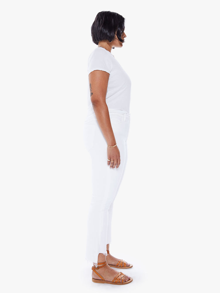 Side view of a womens white wash jean featuring a high rise, bootcut, and a crop step frayed hem.
