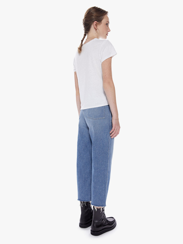 Back view of a woman on a cargo pant features a high rise, wide leg, button fly and frayed ankle-length hem in a a medium wash with thin white stripes and oversized utilitarian pockets on the front and back.