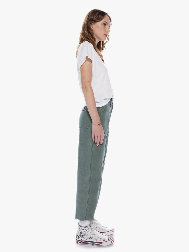 Side view of a woman in a cargo pant featuring a high rise, wide leg, button fly and frayed ankle length hem, made from 100% deadstock fabric in a classic army green hue with tonal buttons