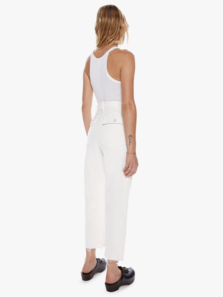 Back Full body view of a woman in a cargo pant features a high rise, wide leg, button fly, and frayed ankle-length hem in a off-white hue with oversized utilitarian pockets on the front and back