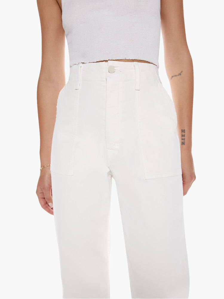 Close up waist view of a woman in a cargo pant features a high rise, wide leg, button fly, and frayed ankle-length hem in a off-white hue with oversized utilitarian pockets on the front and back