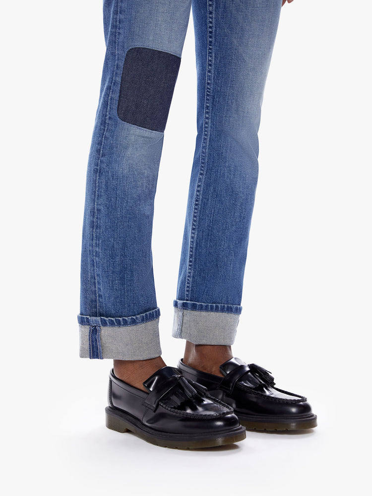 Hem  view of a woman in a mothers original straight leg jean with a mid ride and a cuffed ankle length inseam cut from a semi rigid superior denim in a mid blue wash with fading, whiskering and a patch just above the knee