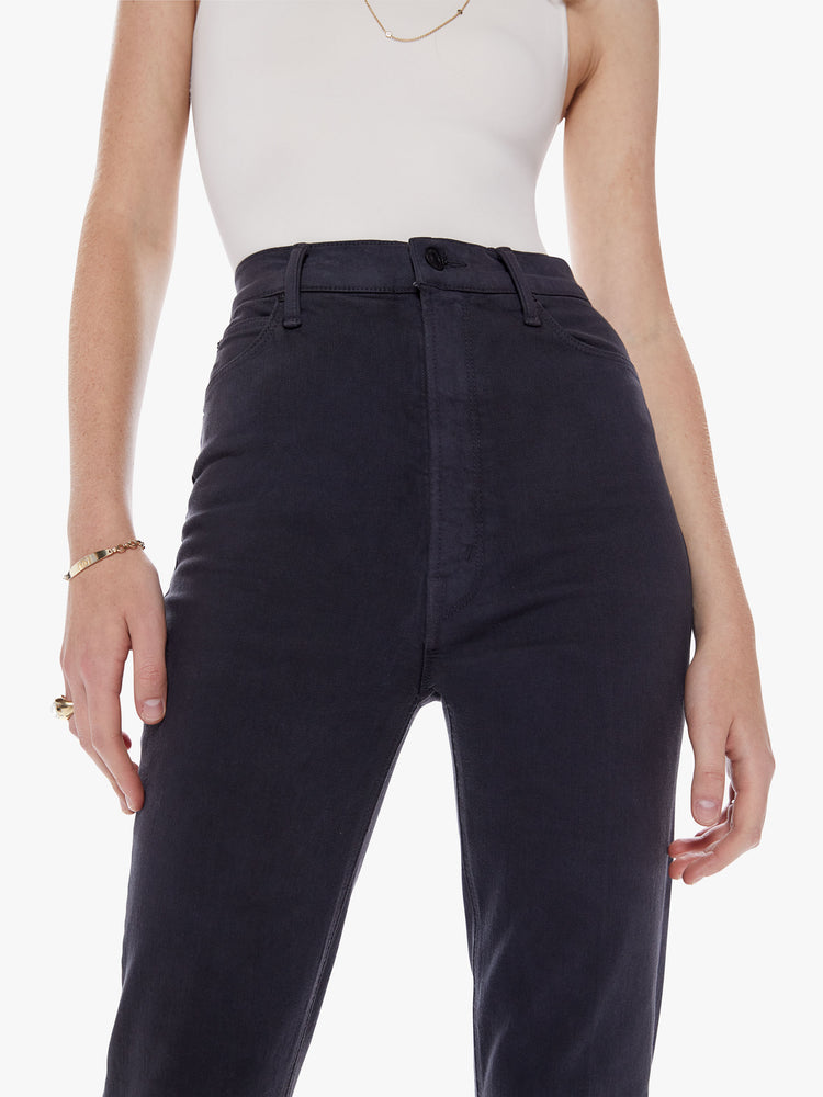 Waist close up view of a woman in a high rise flare with 34 inch inseam and a clean hem cut from a soft cotton fabric in a faded black hue with a tonal hardware for a monochrome look