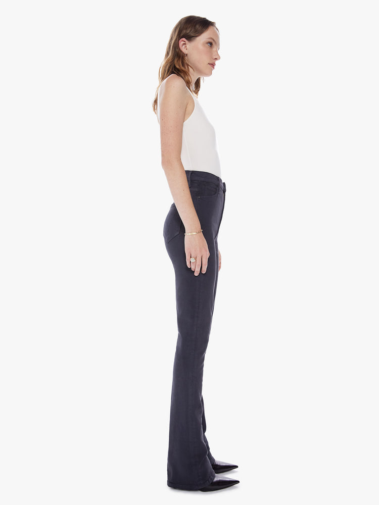 Side view of a woman in a high rise flare with 34 inch inseam and a clean hem cut from a soft cotton fabric in a faded black hue with a tonal hardware for a monochrome look