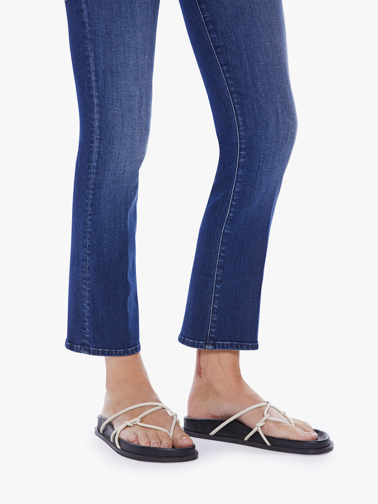 Hem close up view of a woman mid-rise bootcut has an ankle-length inseam and a clean hem in a dark blue wash.