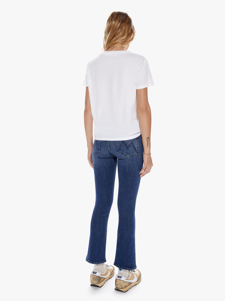 Back full body view of a woman in a mid-rise bootcut, ankle length inseam and clean hem in a indigo blue wash with subtle whiskering and fading