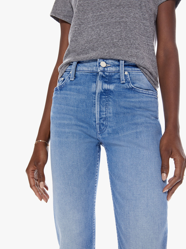 Close up waist view of womens high rise medium blue wash jean with straight leg, ankle length inseam, button fly and fading at the knees.