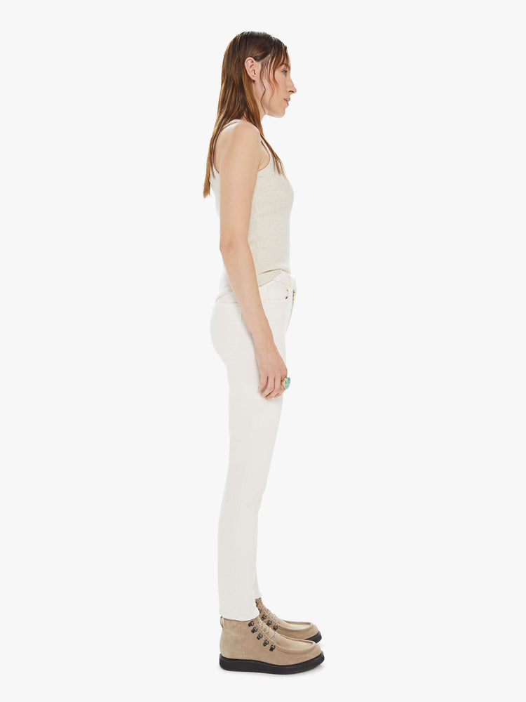 Side view of a womens off white pant featuring a high rise, skinny fit, and a clean ankle length hem.