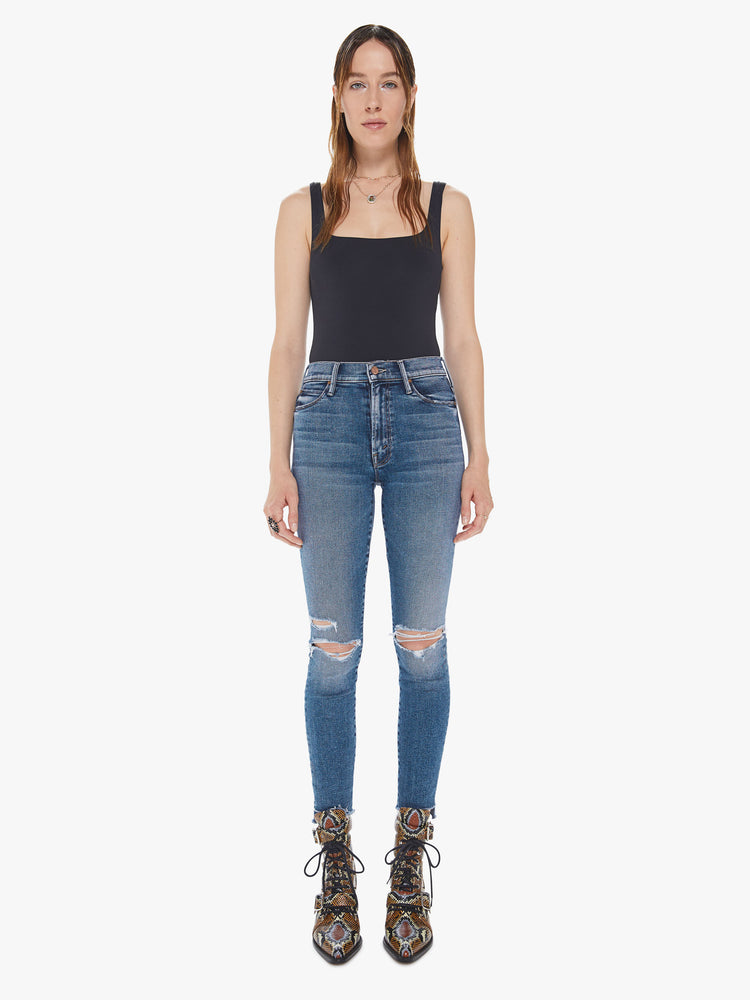 Front view of a womens medium blue wash jean featuring a super high rise, a skinny leg with a ankle length step crop fray.
