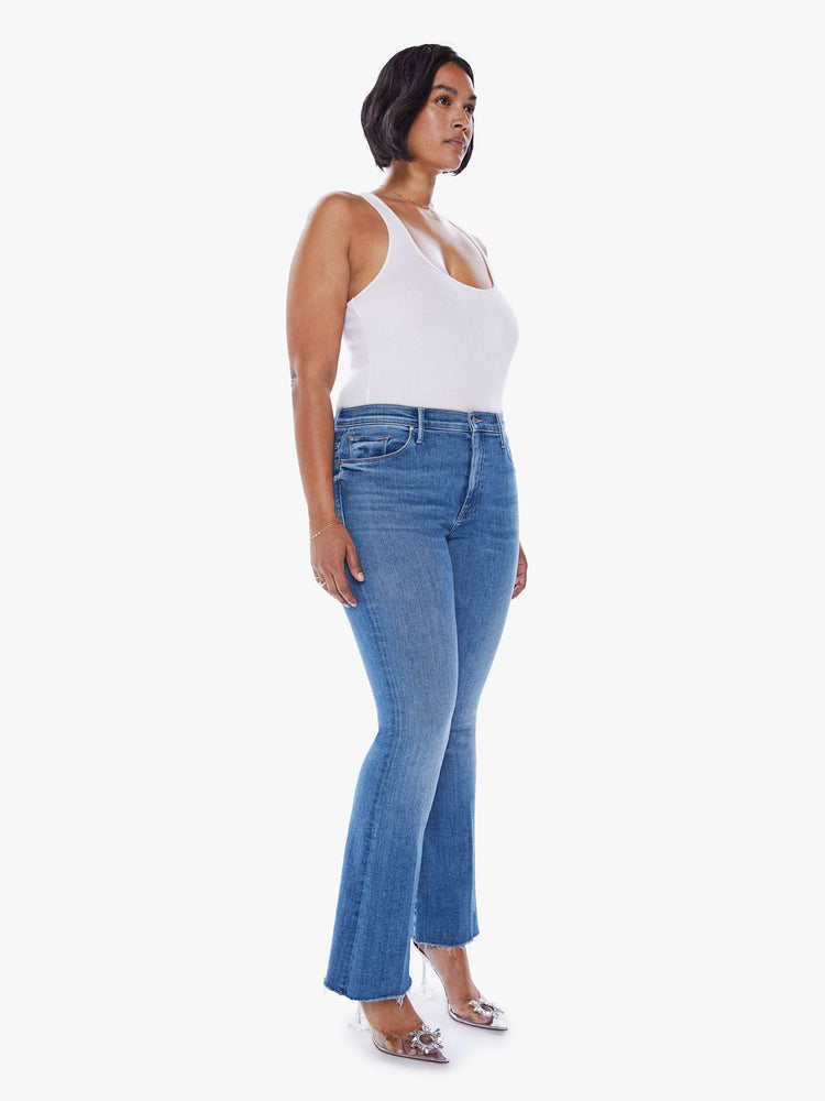 Front view of a womens medium blue wash denim jean featuring a flare leg with a frayed hem.
