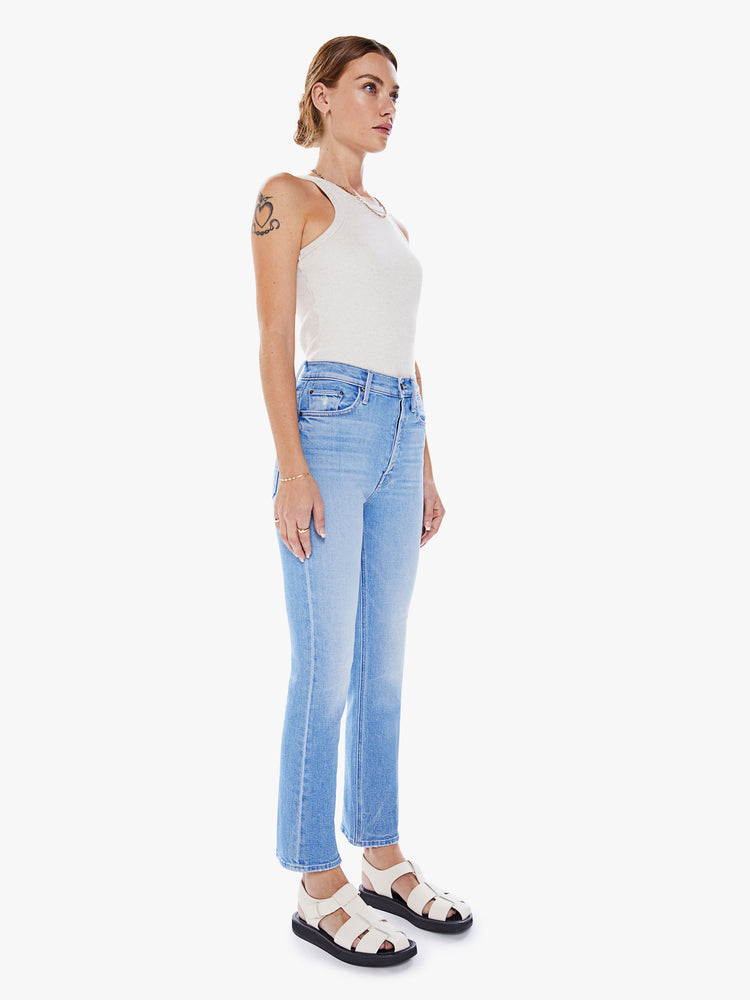 Side angle view of a woman ultra high-rise flare jean with a button fly and a clean ankle-length hem in a light blue wash.