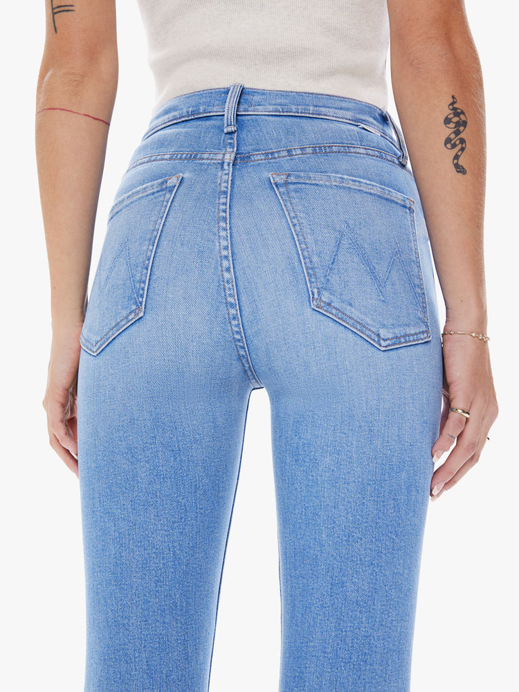 Back close up view of a woman ultra high-rise flare jean with a button fly and a clean ankle-length hem in a light blue wash.