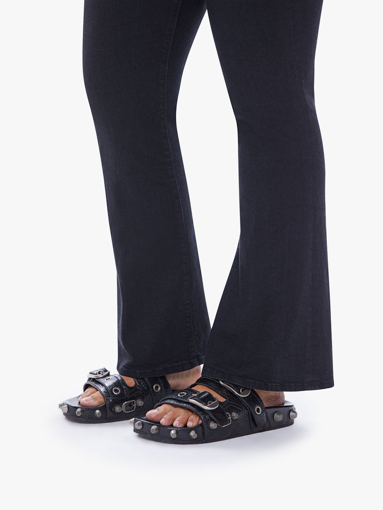 Close up view of a womens black wash jean featuring a flare leg with clean hem.
