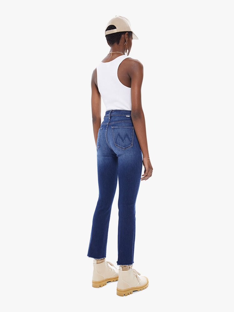 Back view of women's deep blue bootcut jean with fading and a frayed ankle length hem