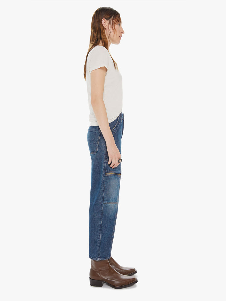 Side view of a womens dark denim wash jean featuring a high rise, cropped length, and cargo details.