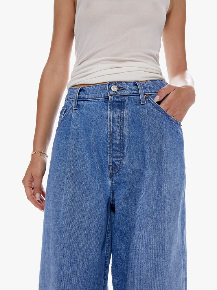 Close up view of a woman in a wide leg jean from snacks from Mothers homeage to throwback styles of 80s and 90s designed to be worn loose and low at the hips, jeans feature a button fly, front pleat for an even roomier fit and clean ankle length inseam in a vintage blue wash