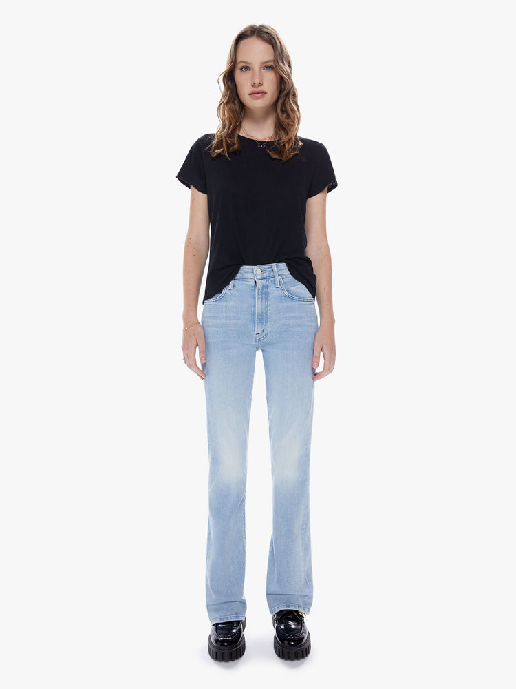 Front full body view of woman in a highrise bootcut jean with a 32 inch inseam and a clean hem cut from stretch denim in a light blue wash with subtle fading and whiskering
