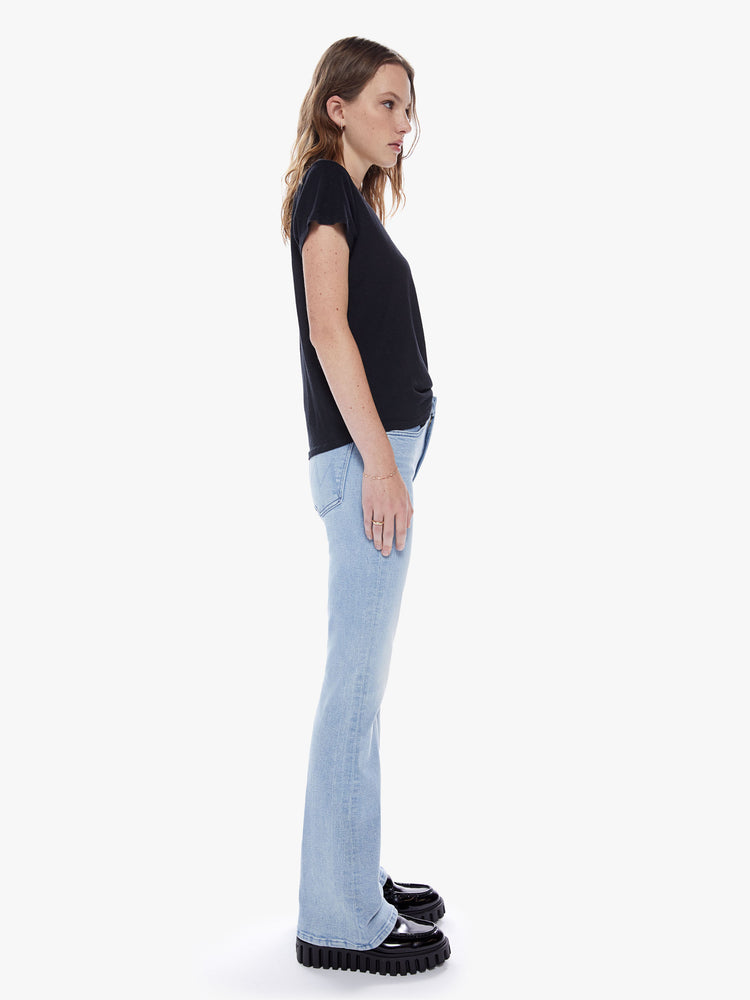 Side full body view of woman in a highrise bootcut jean with a 32 inch inseam and a clean hem cut from stretch denim in a light blue wash with subtle fading and whiskering