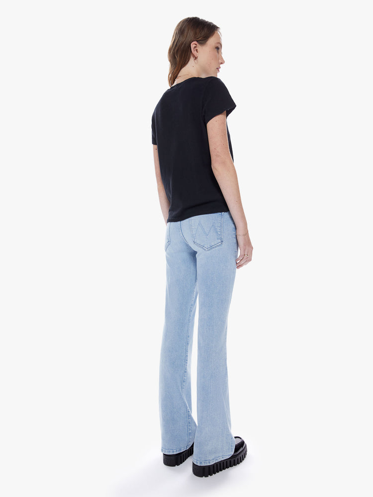 Back full body view of woman in a highrise bootcut jean with a 32 inch inseam and a clean hem cut from stretch denim in a light blue wash with subtle fading and whiskering