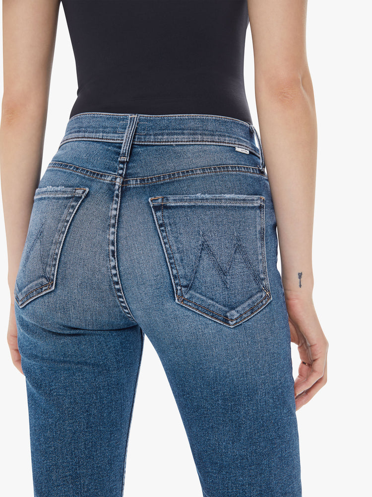 Back close up view of a womens medium blue wash jean featuring a high rise, an ankle length straight leg, and distressed details at the knees.