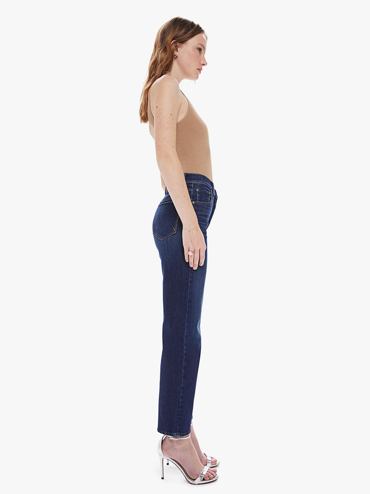 Side view of a women's dark blue high rise straight leg jean with a clean ankle length hem