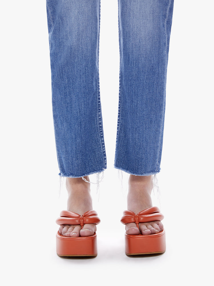 Close up hem view of a woman High-rise jeans with a straight leg, button fly, ankle-length inseam and a frayed hem in a mid blue wash.