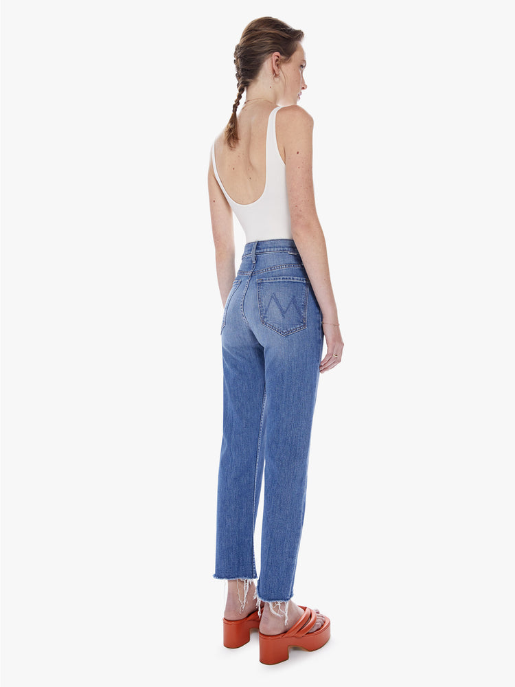 Back view of a woman High-rise jeans with a straight leg, button fly, ankle-length inseam and a frayed hem in a mid blue wash.