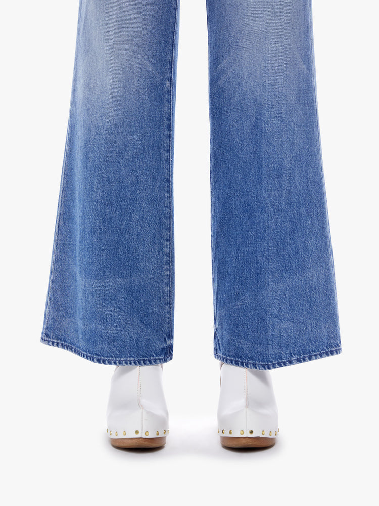 Close up hem view of a woman high-waisted wide leg fit has a button fly, 31-inch inseam and clean hem in a mid blue wash cut from semi-rigid SUPERIOR denim.