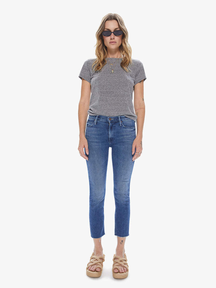 Front view of a woman wearing medium blue wash jeans featuring a mid rise and a frayed cropped hem.