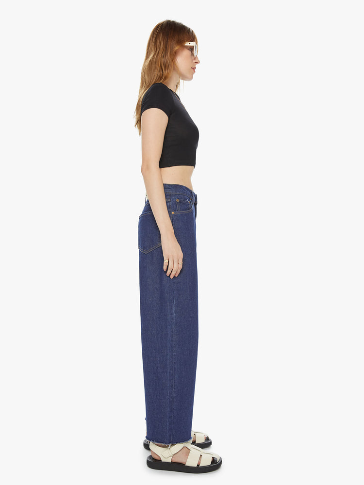 Side view of a women's dark blue wide leg jean with a slouchy fit at the waist and a frayed hem. This style is inspired by the fit of 90s jeans.