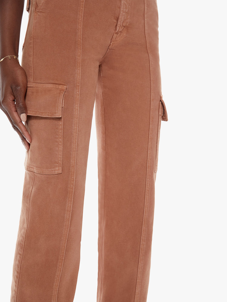 Close up full body view of a woman in high waisted ankle length pants with a wide straight leg, button fly, cargo pockets and seams down the front made from a cotton blend with a touch of stretch in a faded rust hue with tonal hardware