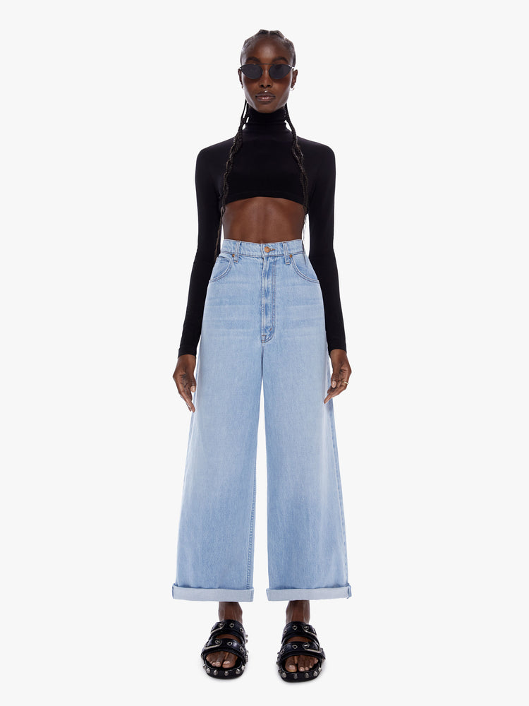 Front full body view of a woman in super wide leg from SNACKS MOTHERS throwback styles of 80s and 90s a high rise jean with a cropped inseam a cuffed hem and a loose roomy fit in a faded light blue wash