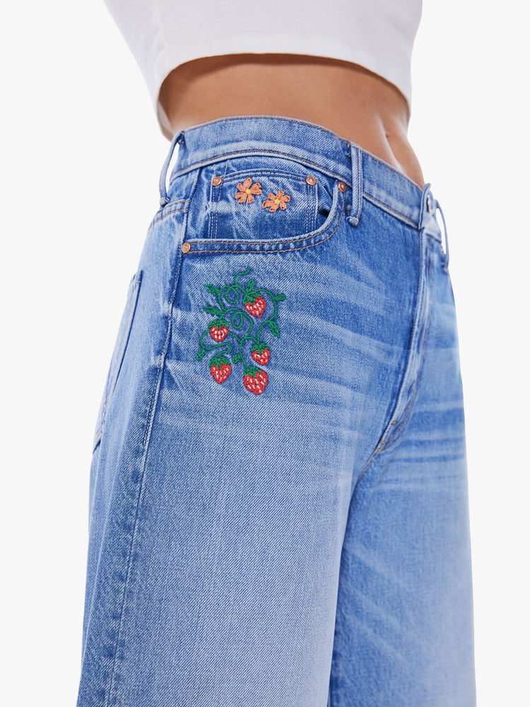 Close up of the colorful garden-inspired embroidery throughout on high-waisted jeans with a loose wide leg and an ankle-length inseam.
