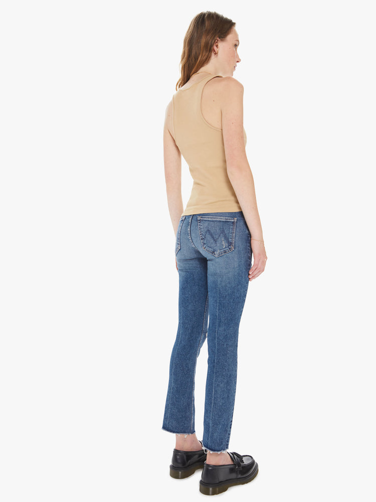 Back view of a women's medium blue mid-rise jean with a slim straight fit and a frayed ankle length hem