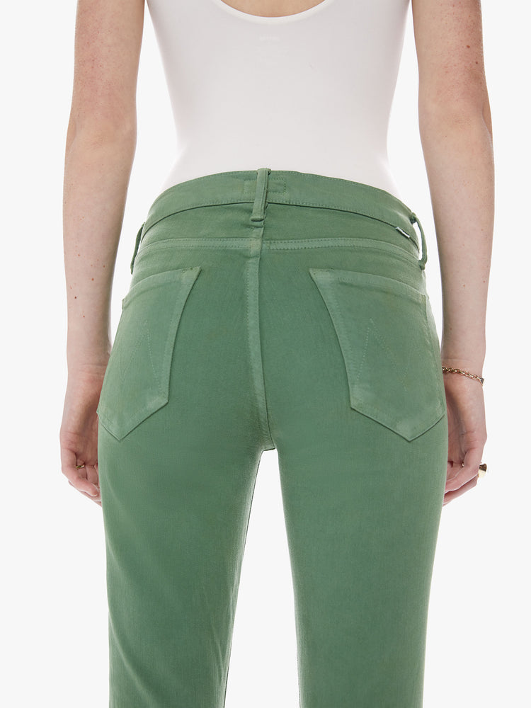 Side back close up view of a mid rise straight leg with an ankle inseam and a frayed hem cut from stretch cotton fabric in a green hue with tonal hardware for a monochrome look