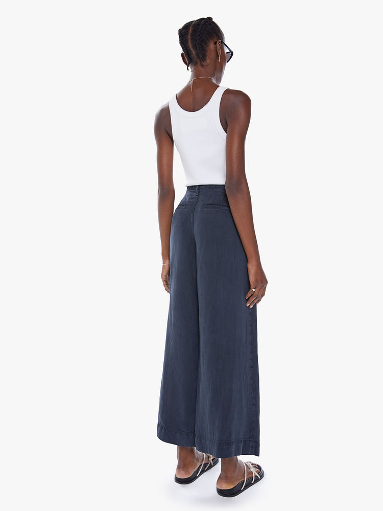 Back view of womans high-waisted wide leg pant with a pleated waistband, back slit pockets, an ankle-length inseam and a clean, thick hem in a faded black hue.
