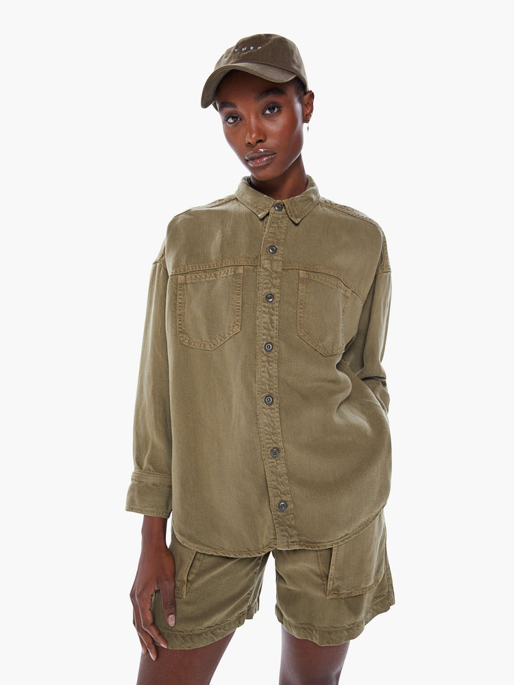 Front view of a woman's ong-sleeve button-up shirt with front patch pockets, drop shoulders and curved hem in an olive green hue.
