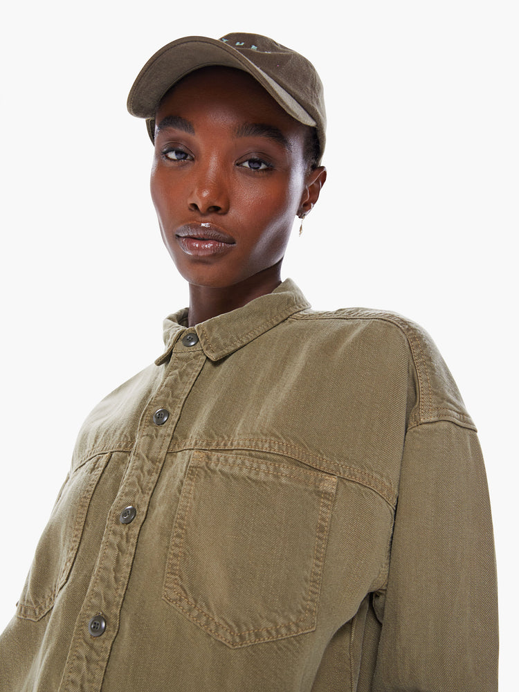 Close up front view of a woman's ong-sleeve button-up shirt with front patch pockets, drop shoulders and curved hem in an olive green hue.