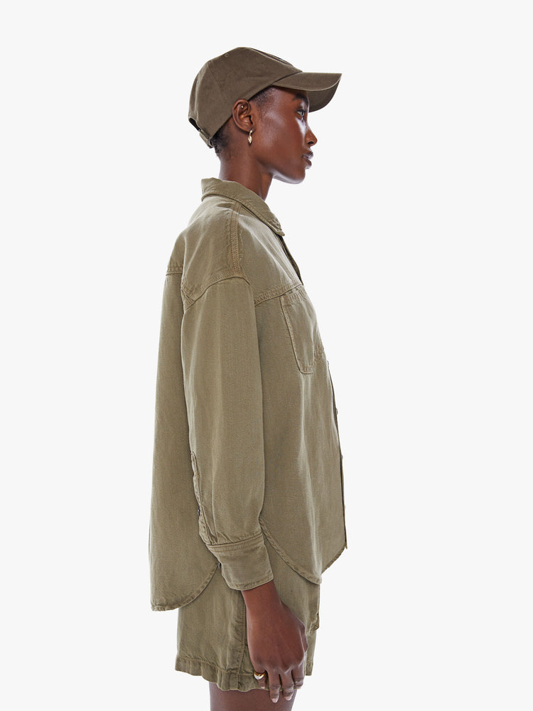 Side view of a woman's ong-sleeve button-up shirt with front patch pockets, drop shoulders and curved hem in an olive green hue.