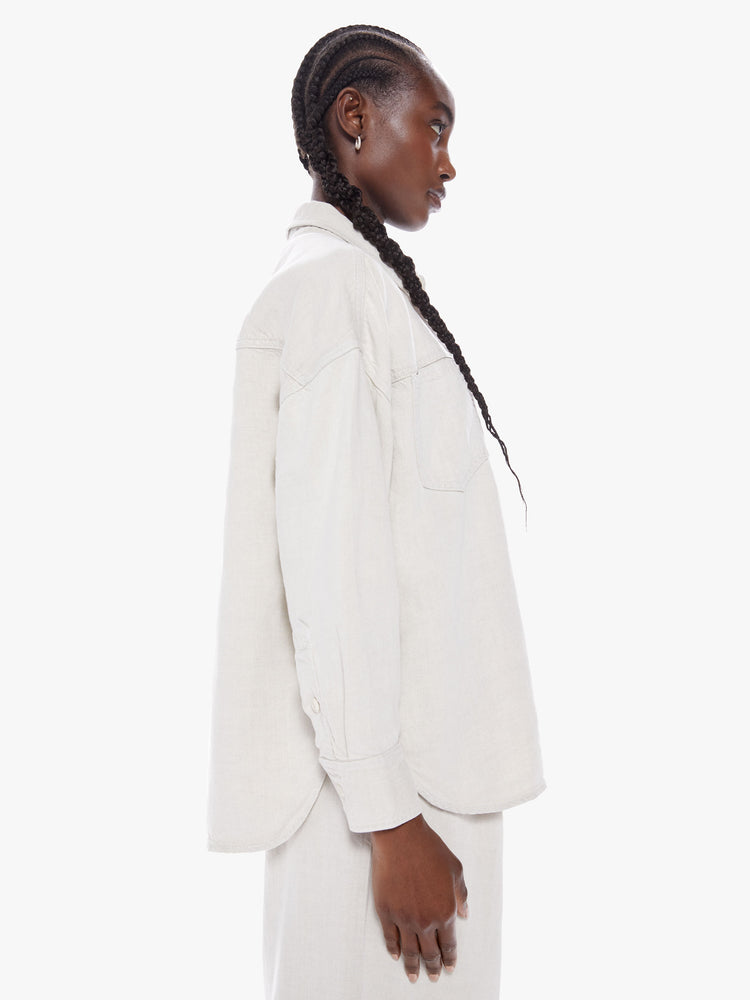 Side view of a woman workwear-inspired button up with drop shoulders, front patch pockets and a slightly curved hem in a creamy hue with tonal hardware for a monochrome look.