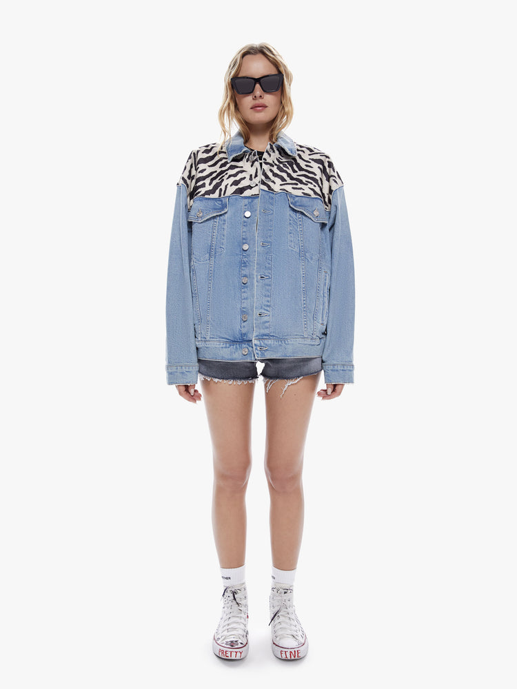 Full body view of a woman in a classic denim jacket with drop shoulders and a boxy, oversized fit cut from a semi rigid superior denim in a light blue wash with soft animal print applique across the shoulder