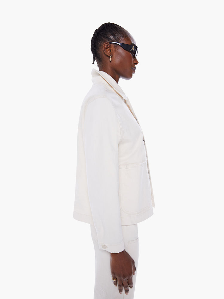 Side of women's denim jacket with oversized front patch pockets, cropped long sleeves and a boxy fit in a creamy white hue.
