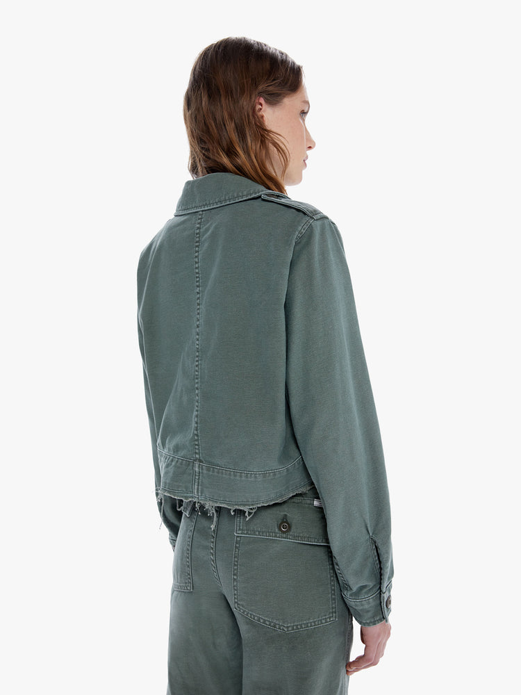 Back close up view of a woman in a military inspired jacket with a front patch pockets and a cropped, fray hem made from 100% cotton deadstock fabric, Roger That is a classic army green hue with tonal buttons and decorative pins on the chest