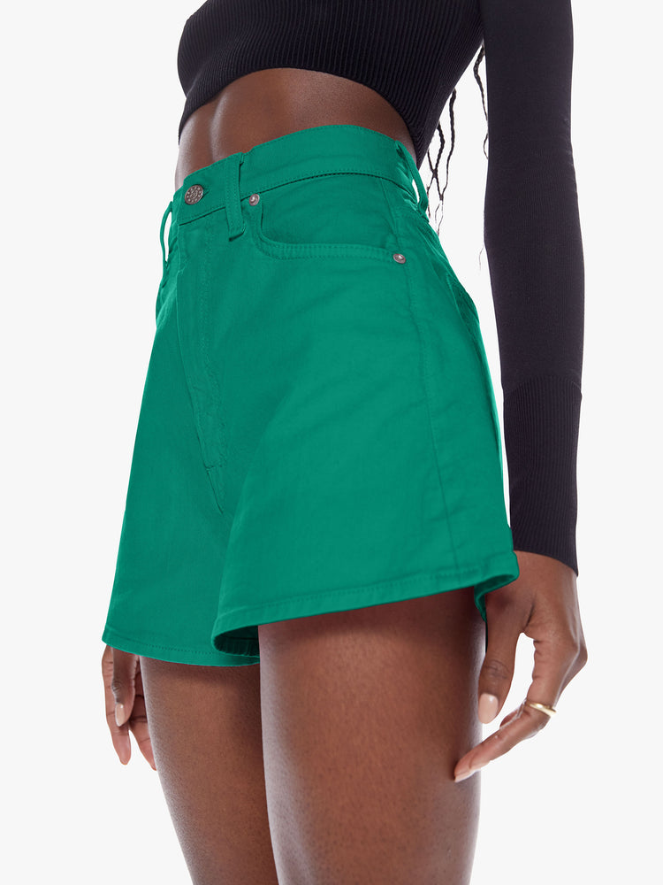 Close up waist view of a woman in denim shorts from SNACKS from mothers homage to throwback styles of the 80s and 90s, the high rise shorts are designed with a super short inseam and a loose wide fit in a forest green hue