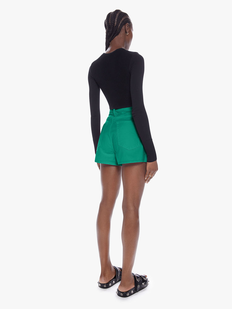 Back full body view of a woman in denim shorts from SNACKS from mothers homage to throwback styles of the 80s and 90s, the high rise shorts are designed with a super short inseam and a loose wide fit in a forest green hue