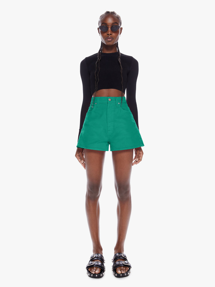 Front full body view of a woman in denim shorts from SNACKS from mothers homage to throwback styles of the 80s and 90s, the high rise shorts are designed with a super short inseam and a loose wide fit in a forest green hue