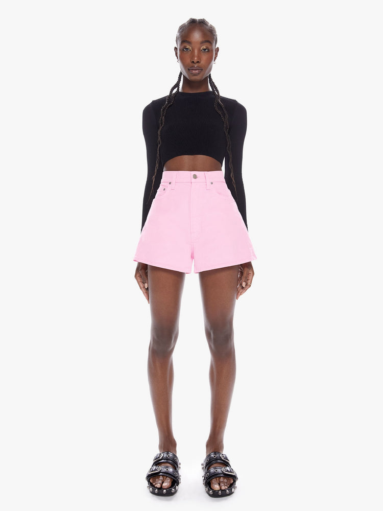Front full body view of a woman in denim shorts from SNACKS from mothers homage to throwback styles of the 80s and 90s, the high rise shorts are designed with a super short inseam and a loose wide fit in a baby pink hue