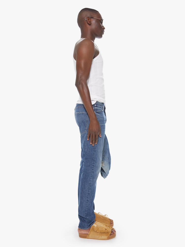 Side view of a men's medium blue straight leg jean with fading and whiskers